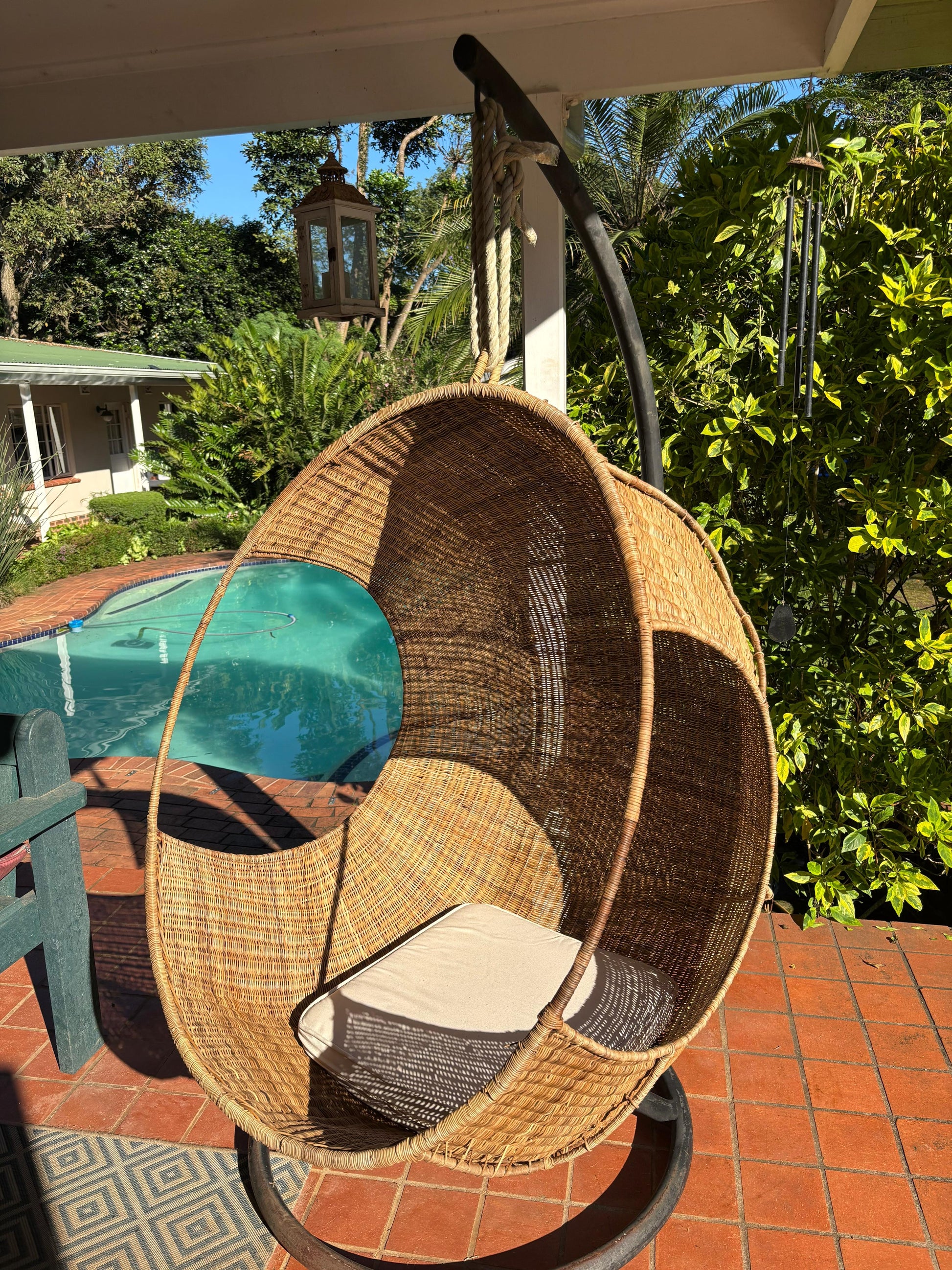 Hand-woven Malawi cane Hanging POD Chair with egg-shaped, cocoon-like structure suspended by sturdy rope, shown in natural finish. The chair features an open weave and rounded form designed as a personal relaxing sanctuary, with customizable detachable cushions (natural, white, or black) for added comfort.