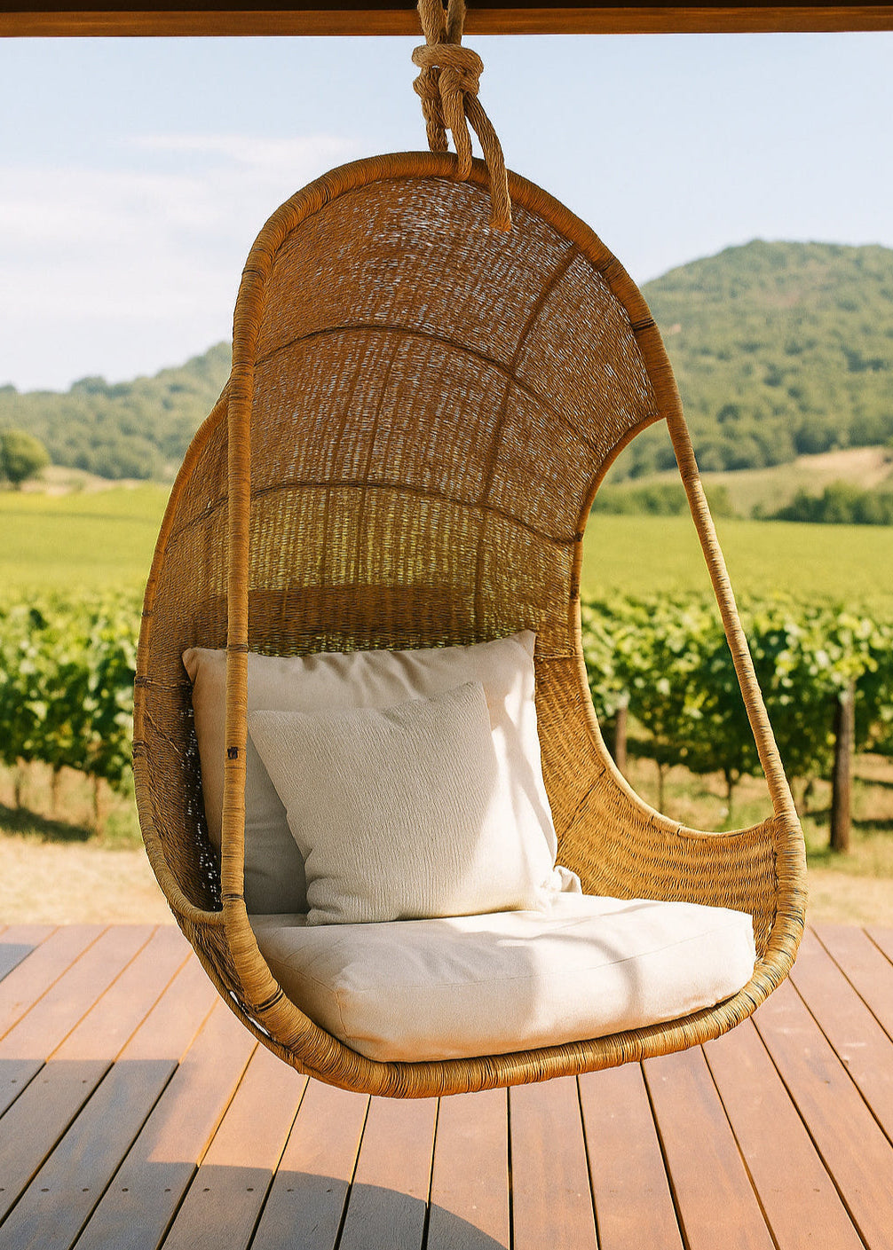 Hanging Egg Chair — A hand-woven, egg-shaped hanging chair crafted from natural Malawi cane. It features a spacious, cocoon-like form and is suspended by a looped rope above. The chair is shown with a soft, plush cushion inside, blending rustic artisanal texture with cozy modern comfort.