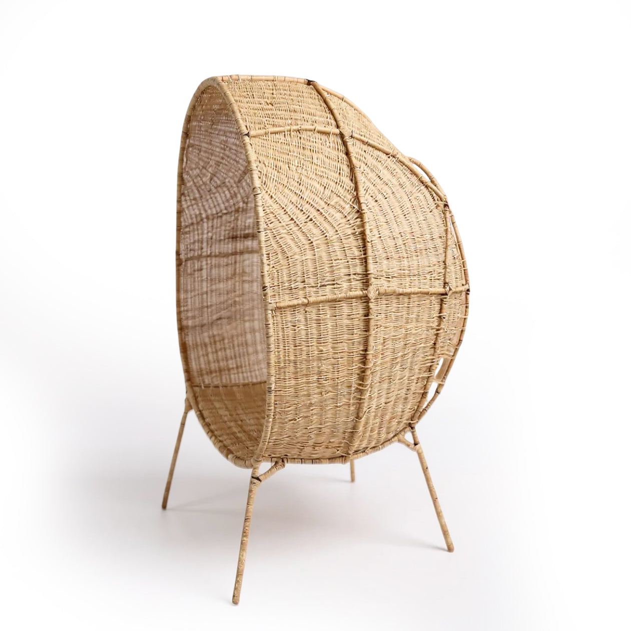 Standing EGG Chair — A handcrafted, egg-shaped chair woven from natural Malawian cane, featuring an elegant cocoon silhouette that rests on a sleek, four-legged metal stand. The chair includes a removable plush cushion (available in natural, white, or black) that enhances comfort and style. This artisanal piece combines organic textures with modern minimalism, making it a striking focal point for both indoor and outdoor spaces.