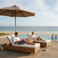Two people relaxing on lounge chairs by a pool with ocean view