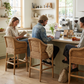 Malawi Furniture - Three handcrafted natural cane Malawian bar stools with white cushions arranged at a bright, modern kitchen island. These classic cane counter stools feature comfortable armrests and bring warm, organic texture and coastal style to a beautifully styled homely cafe.