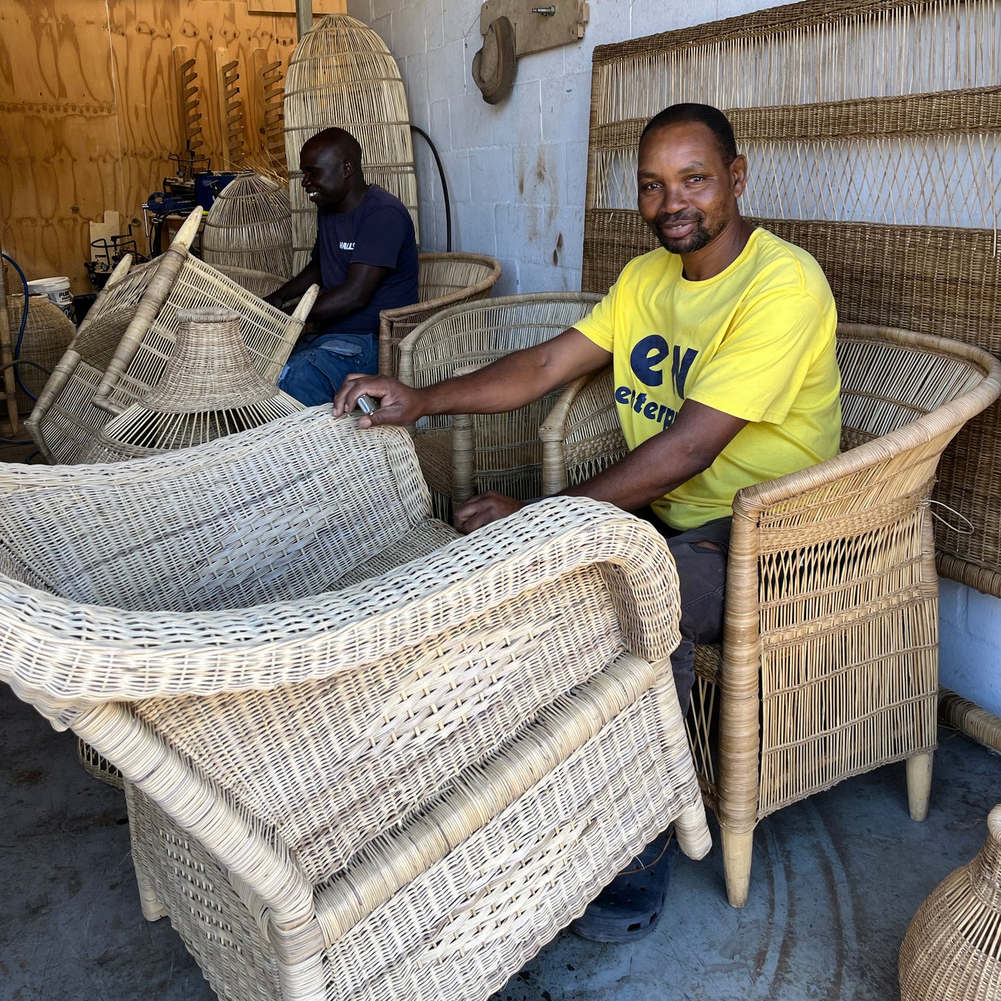 Malawian craftsman refining a classic one seater Malawi chair and large traditional pendant lampshade and single traditional Malawian chairs.