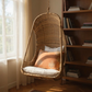 Hanging Egg Chair — A hand-woven, egg-shaped hanging chair crafted from natural Malawi cane. It features a spacious, cocoon-like form and is suspended by a looped rope above. The chair is shown with a soft, plush cushion inside, blending rustic artisanal texture with cozy modern comfort.