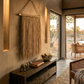 Hanging Grass Wall Decor in an African Safari Lodge. Handcrafted hanging grass wall art by Malawi Furniture, featuring natural dried organic ilala palm and seagrass onto a sustainable wooden dowel. Large 90cm by 1m boho fringed wall hanging in a light natural brown tone for minimalist home decor.