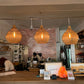Interior of a cafe with wicker pendant lights, brick wall, and customers at the counter.